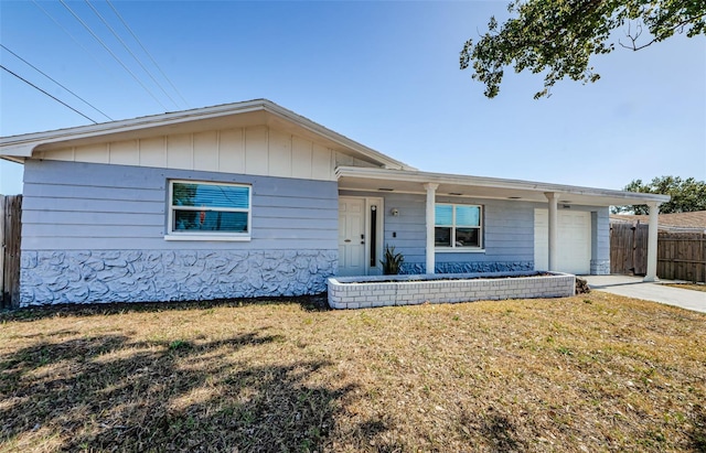 ranch-style home with a front yard, fence, driveway, a garage, and board and batten siding