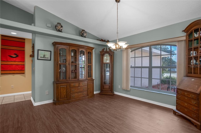 unfurnished dining area featuring dark hardwood / wood-style floors, a chandelier, and vaulted ceiling