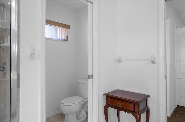 bathroom featuring tile patterned floors, toilet, and a shower with door