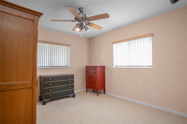 bedroom with multiple windows, ceiling fan, and light carpet