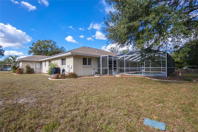 back of property with glass enclosure and a lawn