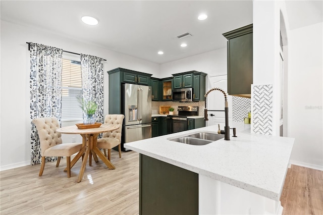 kitchen featuring kitchen peninsula, backsplash, stainless steel appliances, sink, and light hardwood / wood-style flooring