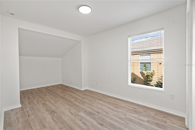 additional living space with light hardwood / wood-style floors and vaulted ceiling