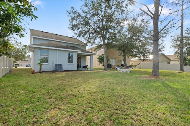 rear view of house with a yard and central AC