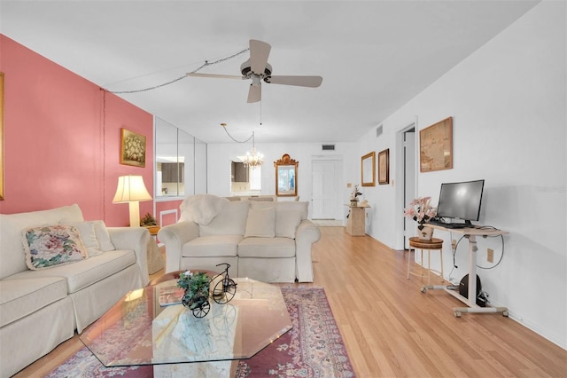 living room with light hardwood / wood-style floors and ceiling fan with notable chandelier