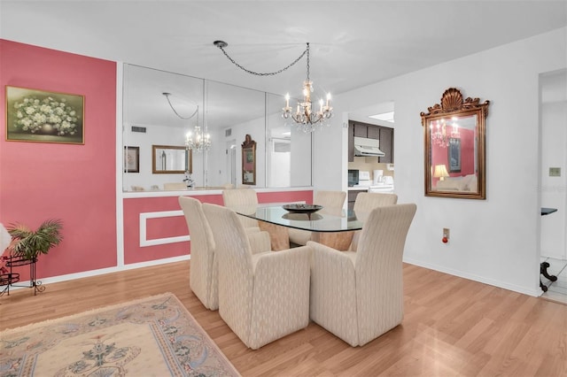 dining space with light hardwood / wood-style floors and an inviting chandelier