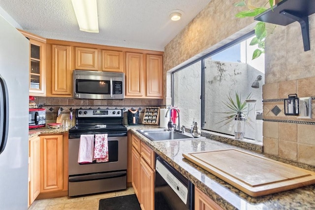 kitchen with backsplash, light stone countertops, sink, and stainless steel appliances