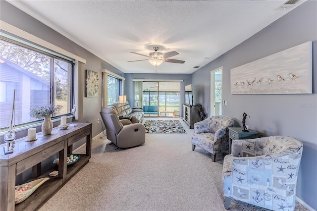 living room featuring carpet, ceiling fan, and a textured ceiling