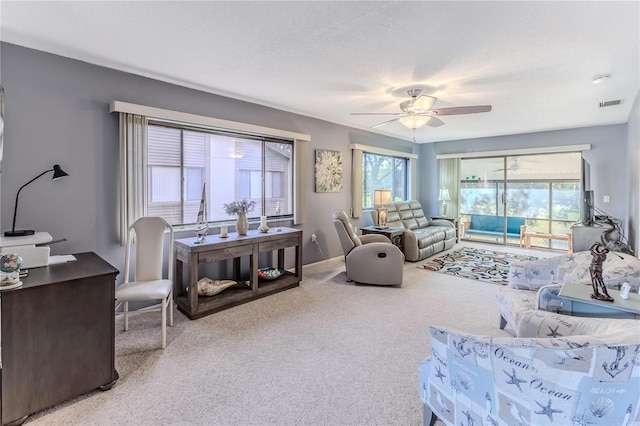 carpeted living room featuring ceiling fan and a textured ceiling