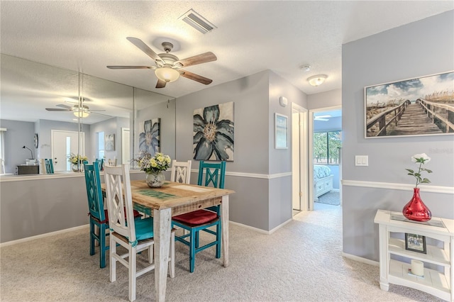 dining space with a textured ceiling and light carpet