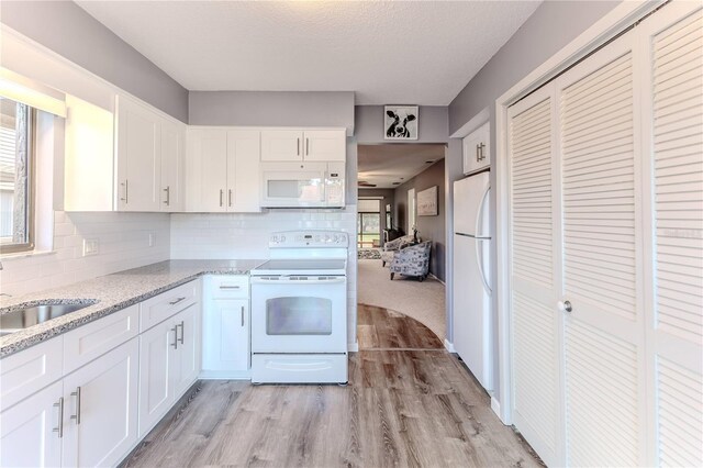 12814 Wedgewood Way Unit C, Hudson, FL 34667 - kitchen featuring white appliances, light wood-style flooring, white cabinetry, and backsplash
