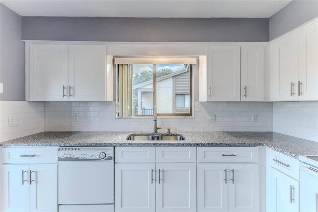 12814 Wedgewood Way Unit C, Hudson, FL 34667 - kitchen with white dishwasher, white cabinetry, light stone counters, and decorative backsplash