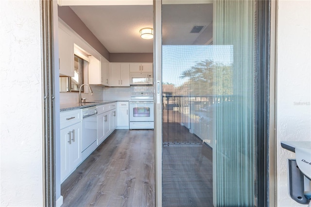 kitchen featuring a wealth of natural light, white appliances, sink, wood-type flooring, and white cabinetry