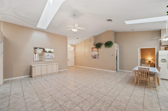 interior space with ceiling fan with notable chandelier, light tile patterned flooring, and a skylight