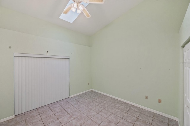 tiled spare room with lofted ceiling with skylight and ceiling fan