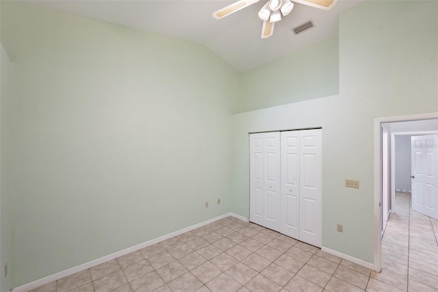 unfurnished bedroom with light tile patterned floors, a closet, ceiling fan, and lofted ceiling