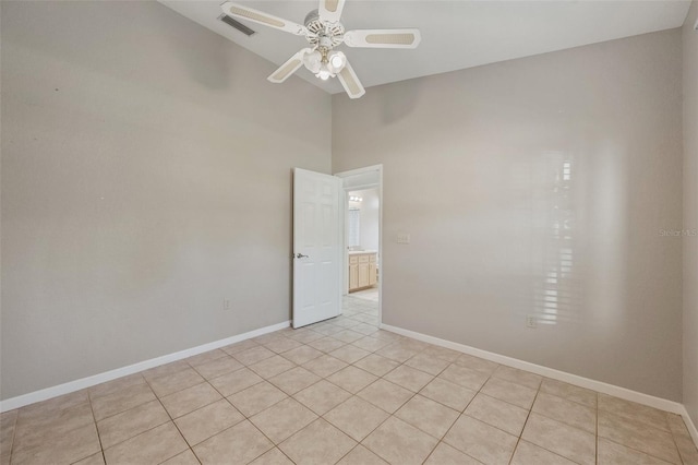 tiled spare room with ceiling fan and a high ceiling