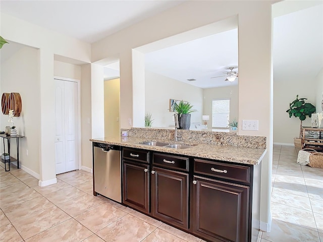 kitchen featuring ceiling fan, sink, light stone counters, stainless steel dishwasher, and dark brown cabinets