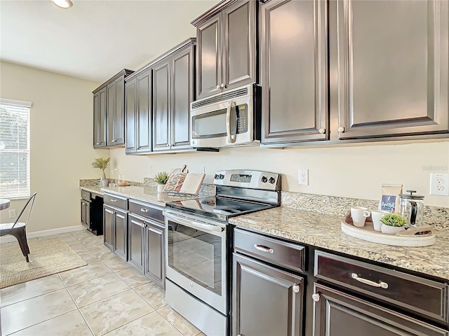 kitchen featuring light stone counters, dark brown cabinets, light tile patterned floors, and stainless steel appliances