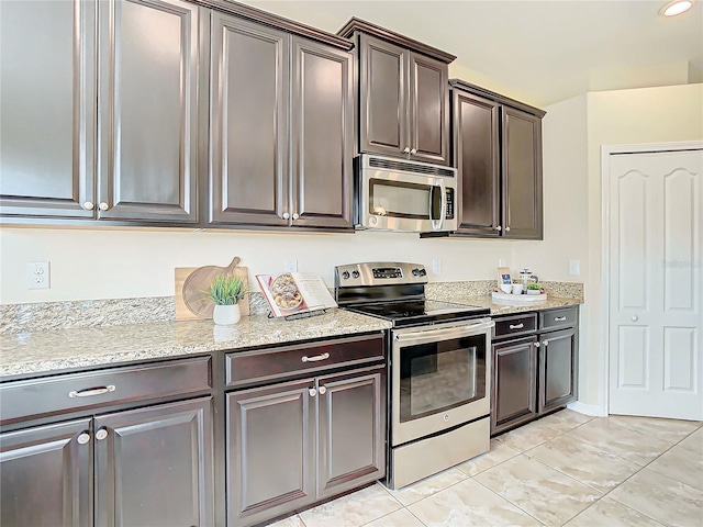 kitchen with dark brown cabinets, light stone counters, light tile patterned floors, and stainless steel appliances