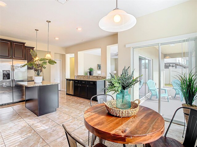 kitchen featuring dark brown cabinets, light stone countertops, stainless steel appliances, and decorative light fixtures