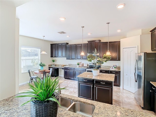 kitchen featuring dark brown cabinetry, light stone countertops, decorative light fixtures, and appliances with stainless steel finishes