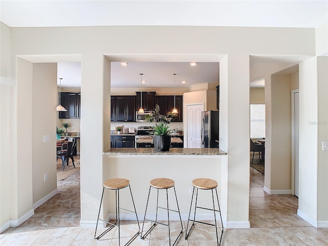 kitchen featuring a breakfast bar, light stone counters, kitchen peninsula, and appliances with stainless steel finishes