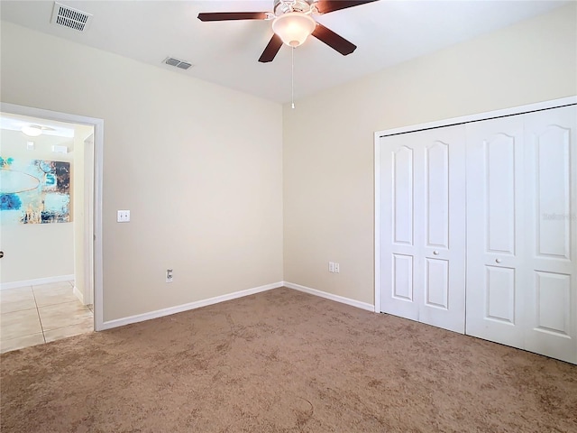 unfurnished bedroom with a closet, light colored carpet, and ceiling fan