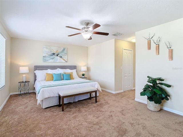 bedroom with ceiling fan, light colored carpet, and a closet