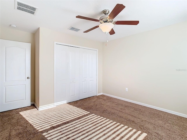 unfurnished bedroom with ceiling fan, dark carpet, and a closet