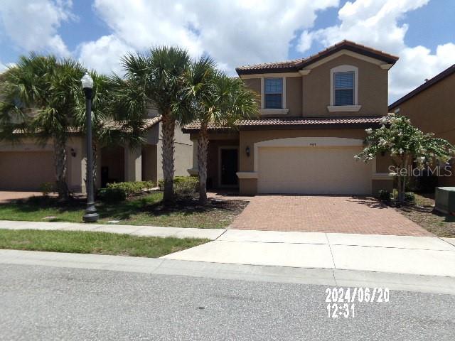 5537 Misty Oak Cir, Davenport, FL 33837 - mediterranean / spanish home with a tiled roof, stucco siding, decorative driveway, and an attached garage