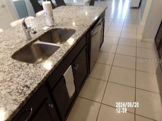 5537 Misty Oak Cir, Davenport, FL 33837 - kitchen featuring light tile patterned floors, stainless steel dishwasher, and light stone countertops