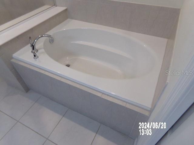 bathroom with tile patterned floors and tiled tub