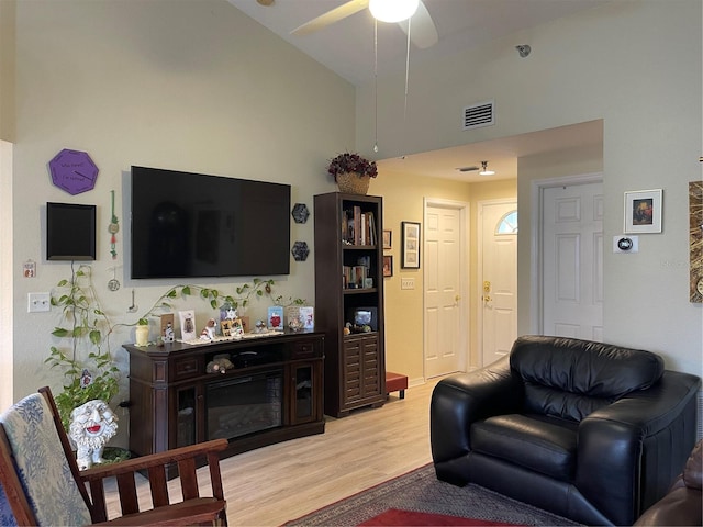 living room with ceiling fan, light hardwood / wood-style floors, and lofted ceiling