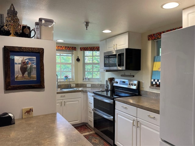 kitchen featuring appliances with stainless steel finishes, a textured ceiling, white cabinetry, and sink