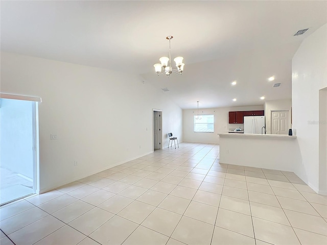 unfurnished living room with a notable chandelier, light tile patterned floors, and vaulted ceiling