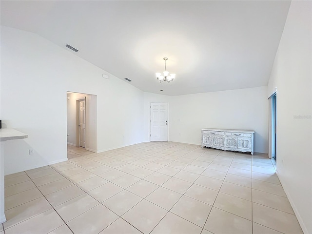 tiled spare room featuring a chandelier and lofted ceiling