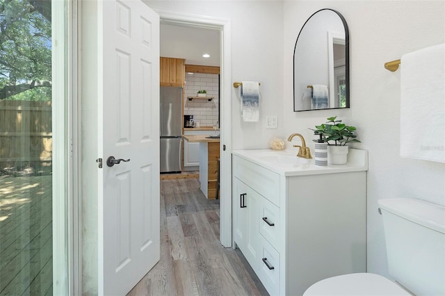 bathroom featuring vanity, tasteful backsplash, toilet, and hardwood / wood-style flooring