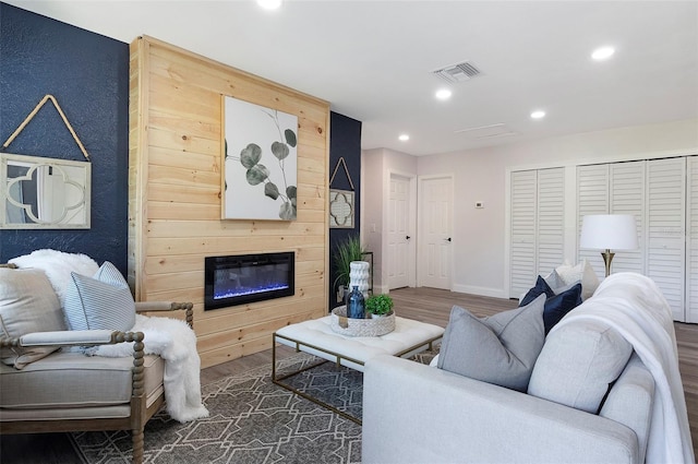 living room featuring a large fireplace and dark wood-type flooring