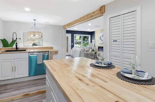 kitchen with wood counters, white cabinets, sink, dishwasher, and hanging light fixtures