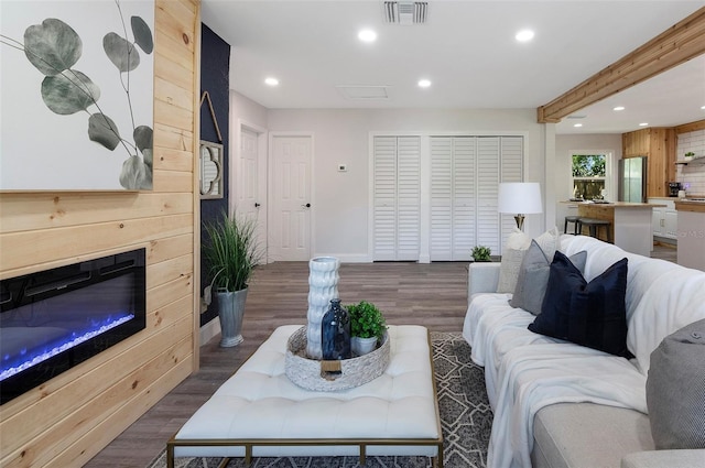 living room with wood walls, beamed ceiling, and dark wood-type flooring