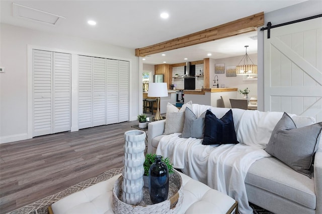 living room with beamed ceiling, wood-type flooring, and a barn door