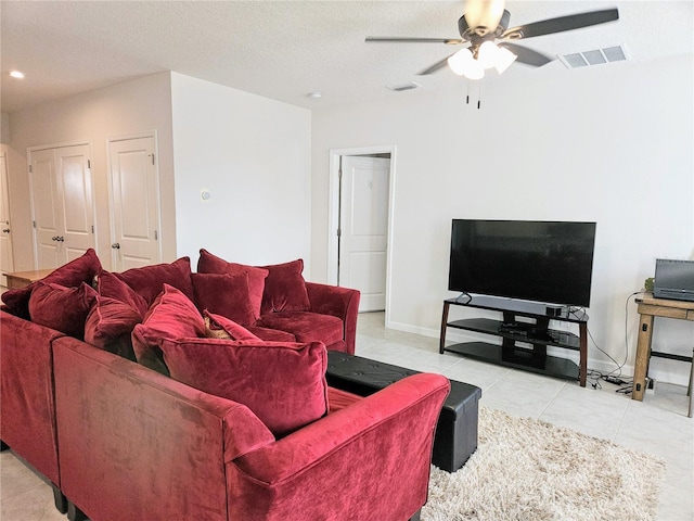 living room featuring light tile patterned floors, a textured ceiling, and ceiling fan