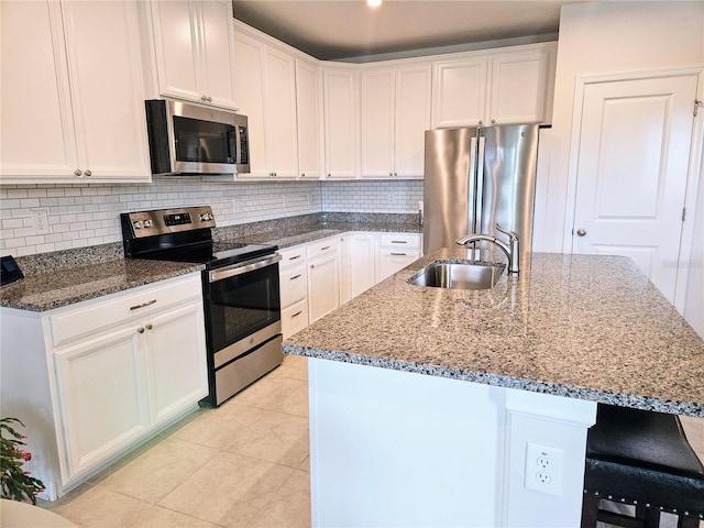 kitchen featuring white cabinetry, an island with sink, sink, backsplash, and stainless steel appliances