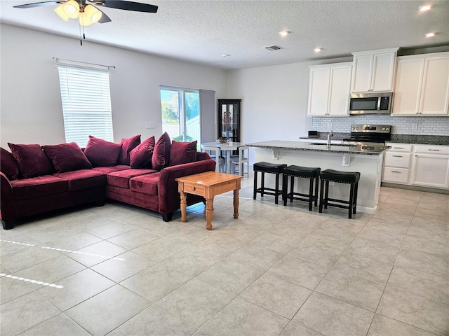 living area featuring recessed lighting, visible vents, a textured ceiling, and a ceiling fan