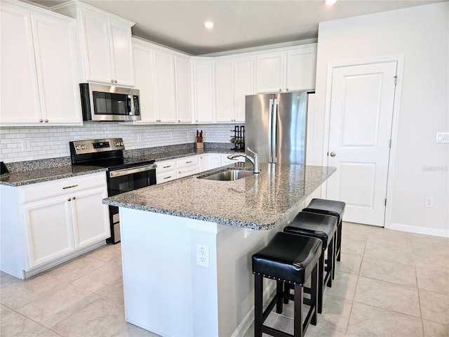 kitchen featuring tasteful backsplash, stainless steel appliances, dark stone counters, and a sink