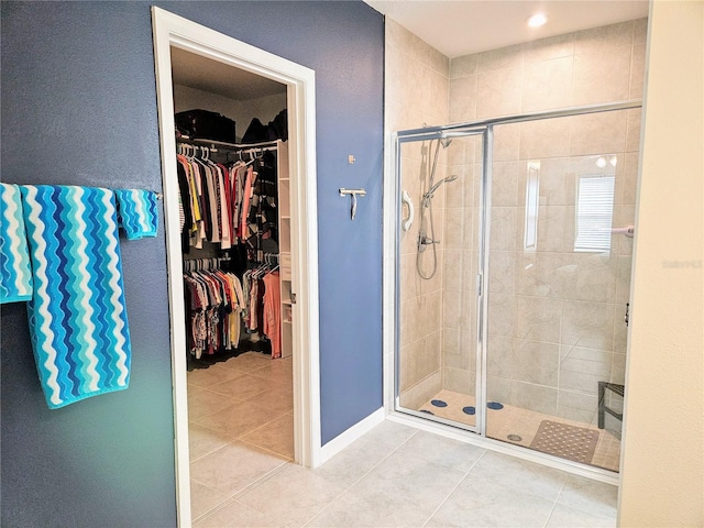 bathroom with tile patterned floors, a spacious closet, and a stall shower