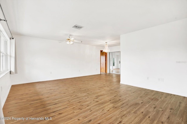 empty room with hardwood / wood-style flooring and ceiling fan with notable chandelier