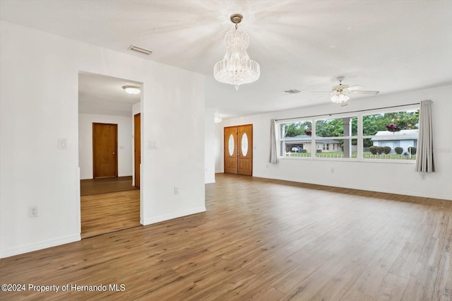 unfurnished living room featuring ceiling fan with notable chandelier and hardwood / wood-style flooring