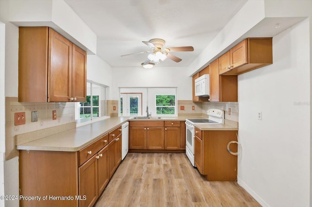 kitchen with light wood-type flooring, white appliances, tasteful backsplash, and sink